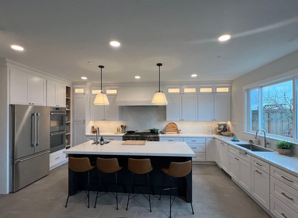 Modern kitchen design with white cabinetry, marble island, and pendant lighting.