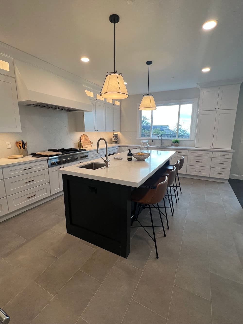 Modern kitchen with white cabinetry, black island, and stylish pendant lighting.