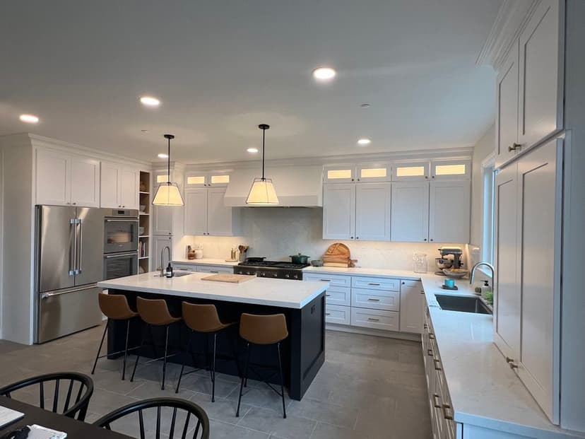 Modern kitchen featuring white cabinetry, large island, pendant lighting, and stainless appliances.