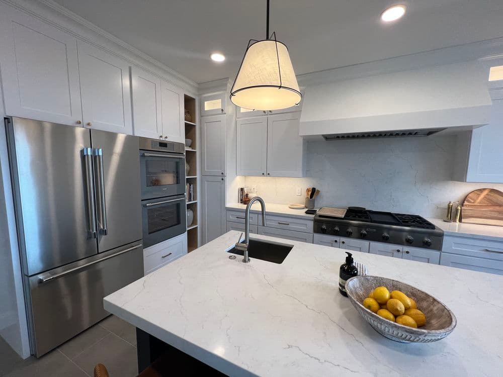 Modern kitchen with stainless steel appliances, marble countertops, and ambient lighting.