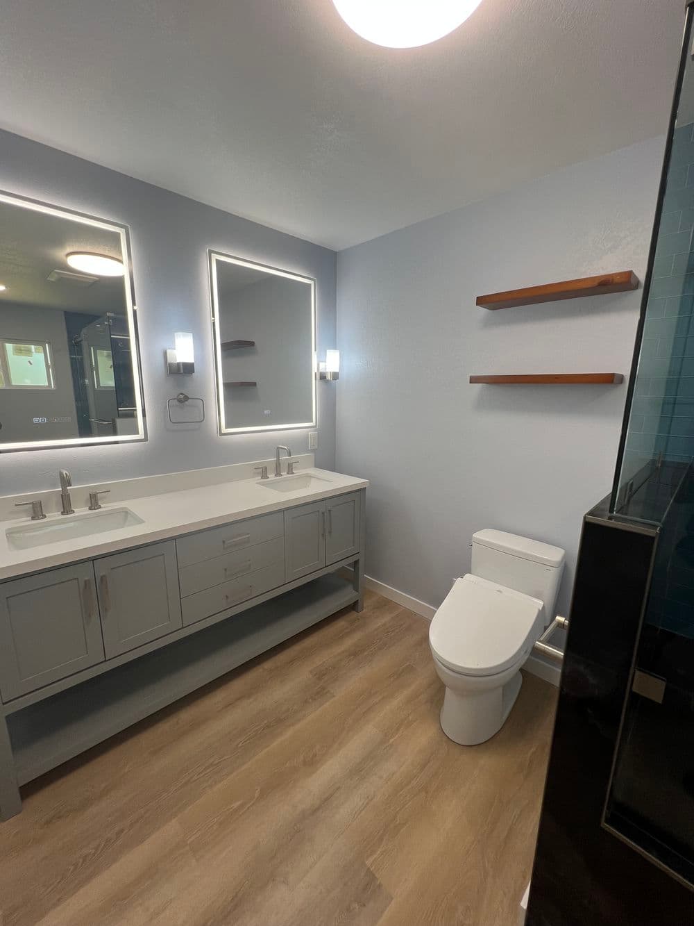 Modern bathroom design with double vanity, large mirrors, and sleek shelving.