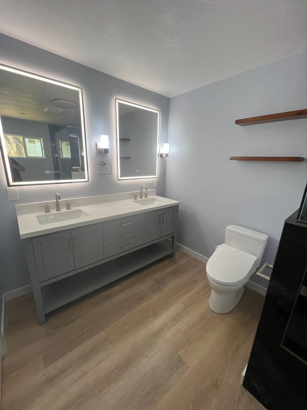 Modern bathroom with dual mirrors, sleek vanity, and contemporary flooring.