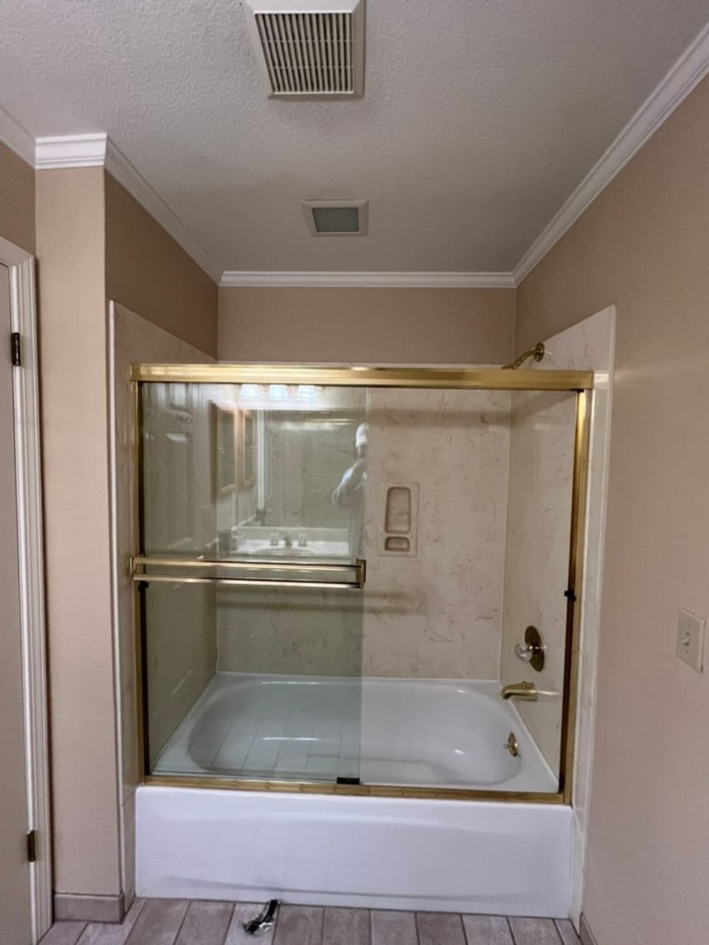 Modern bathroom featuring a glass shower enclosure with gold accents and a bathtub.