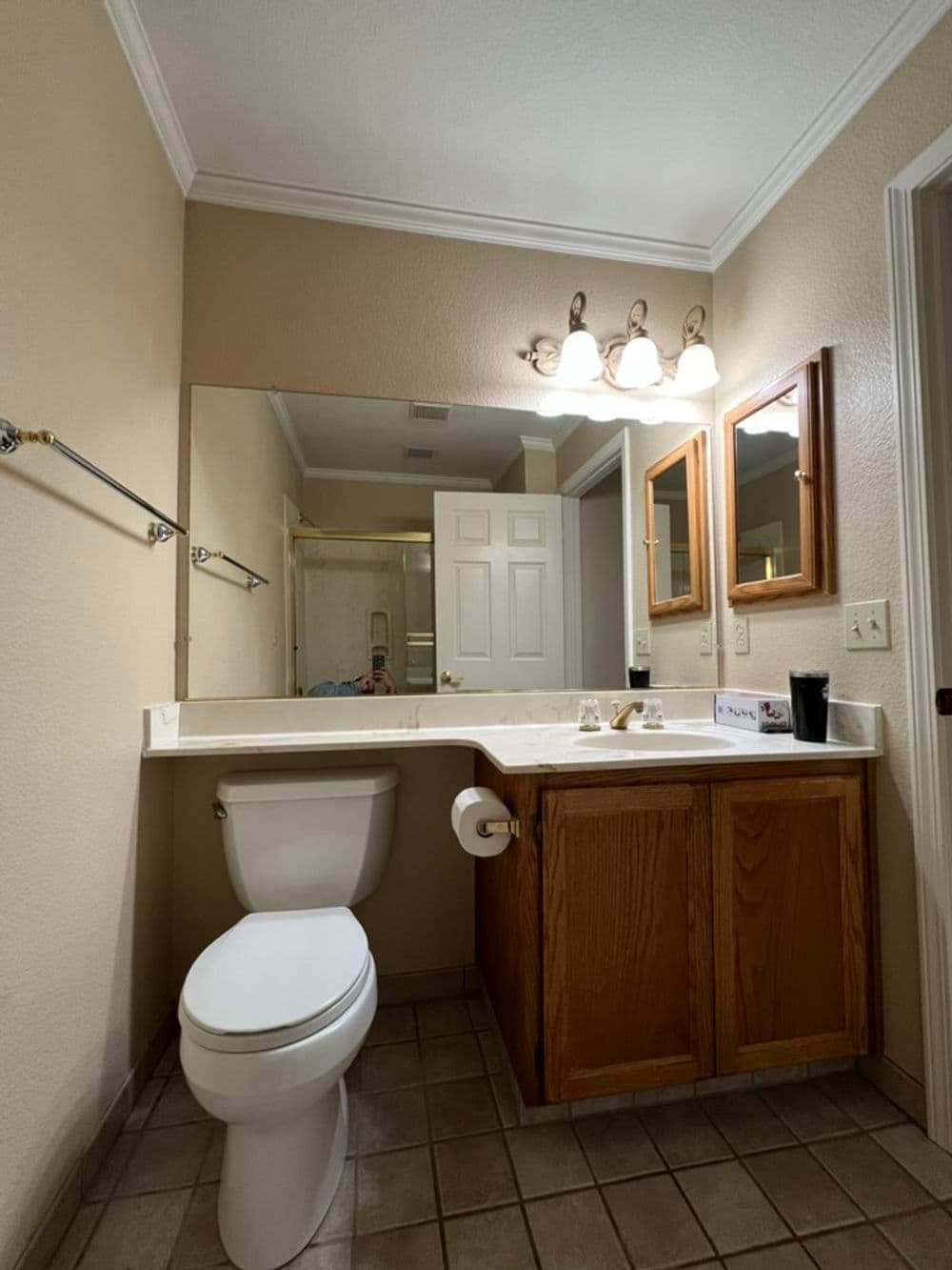 Modern bathroom with white toilet, wooden cabinetry, double mirrors, and bright lighting.