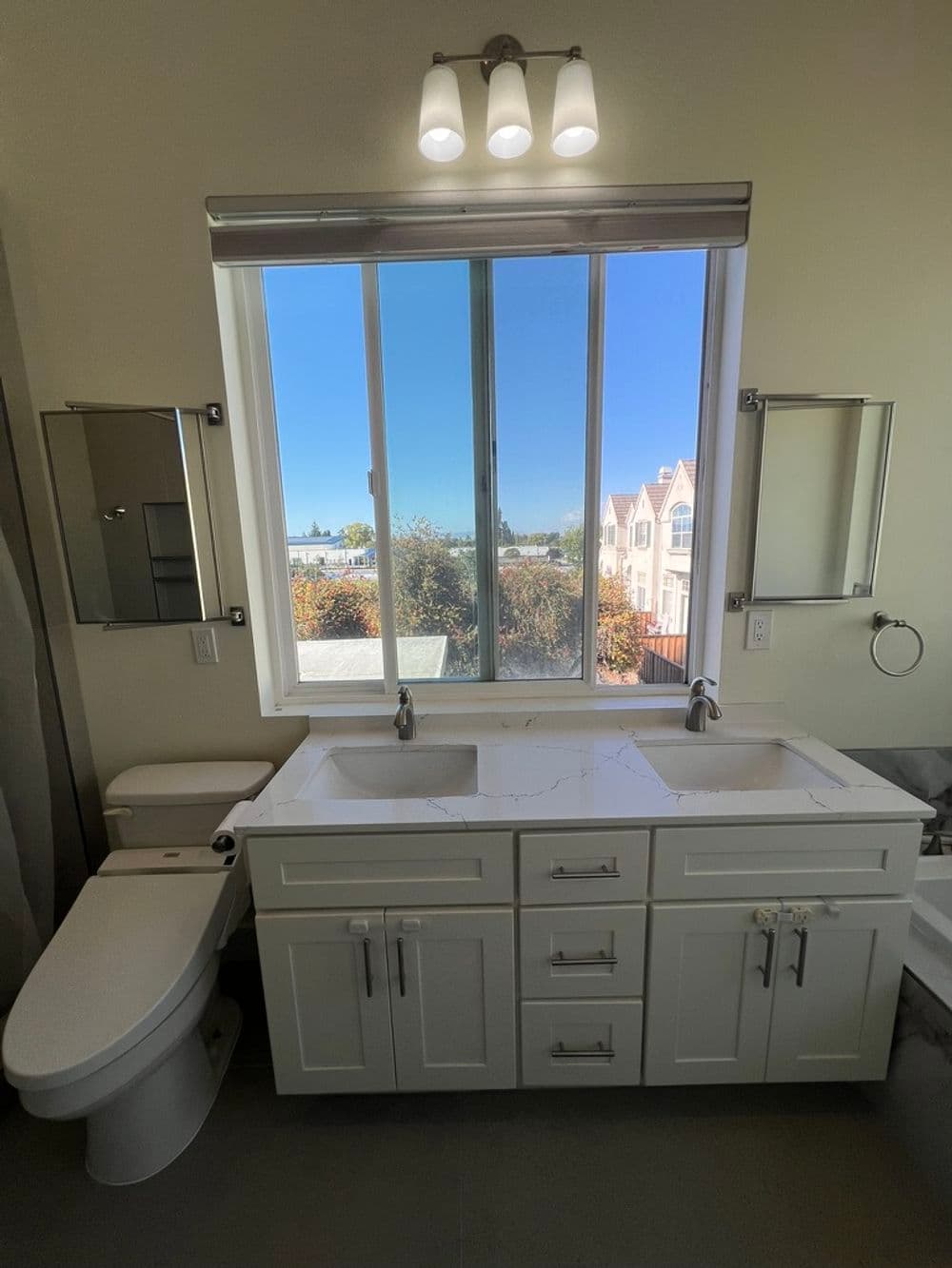 Modern bathroom with double sink vanity, large window, and stylish fixtures.