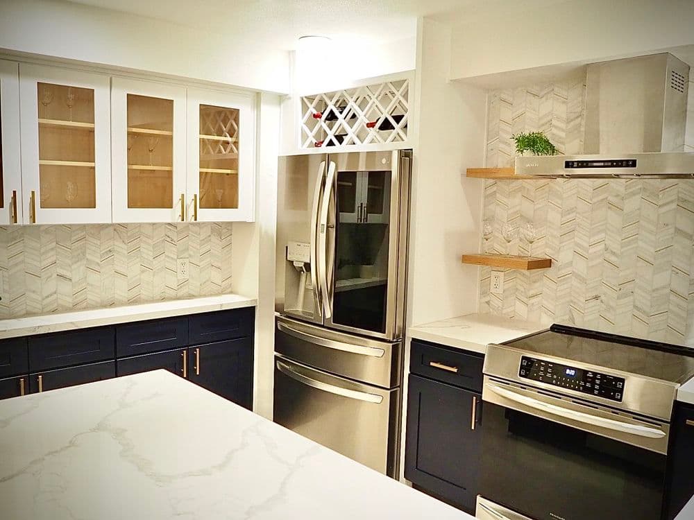 Modern kitchen with stainless steel appliances, white cabinets, and herringbone backsplash.
