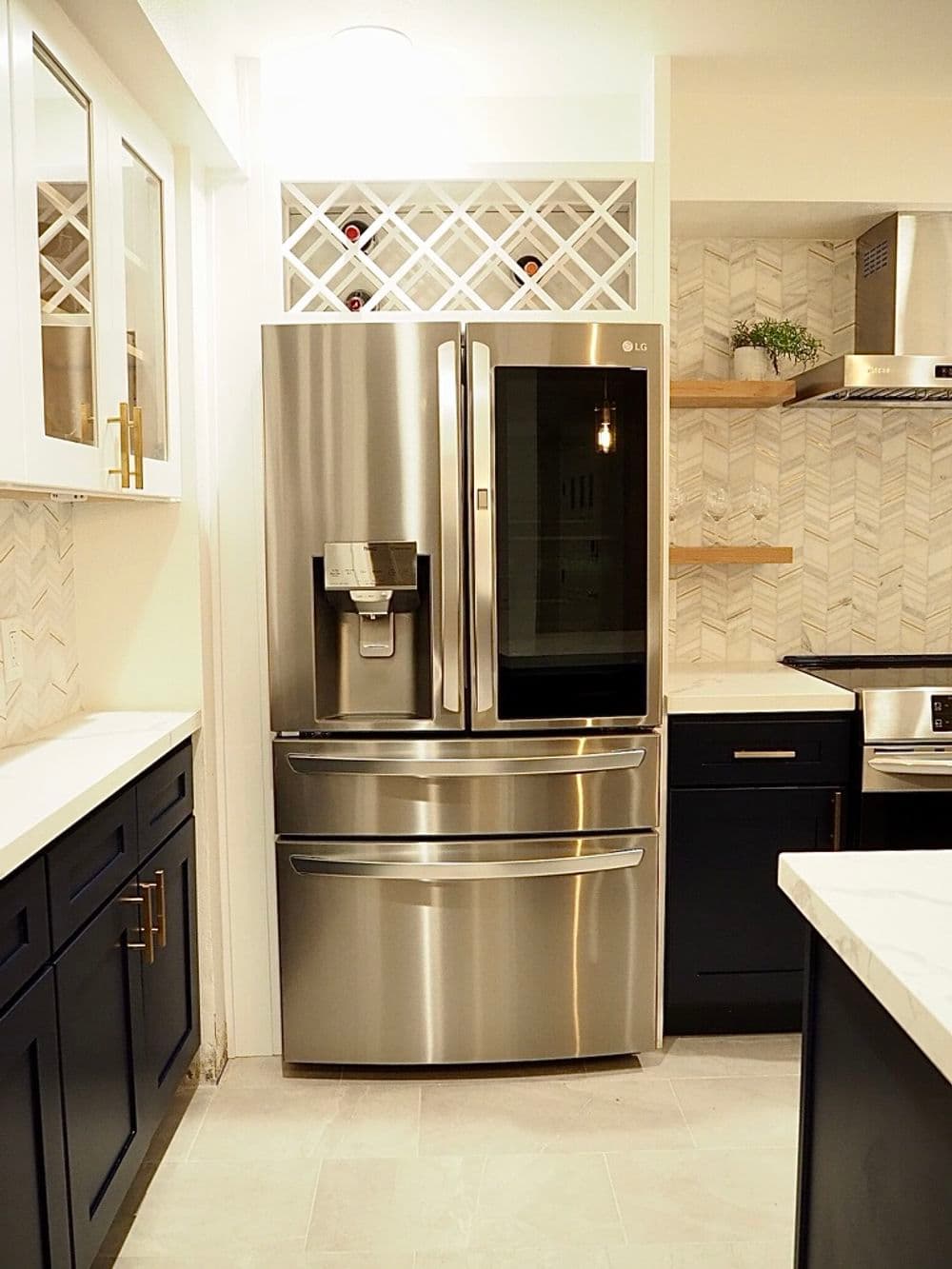 Modern LG stainless steel fridge in stylish kitchen with white and navy cabinetry.