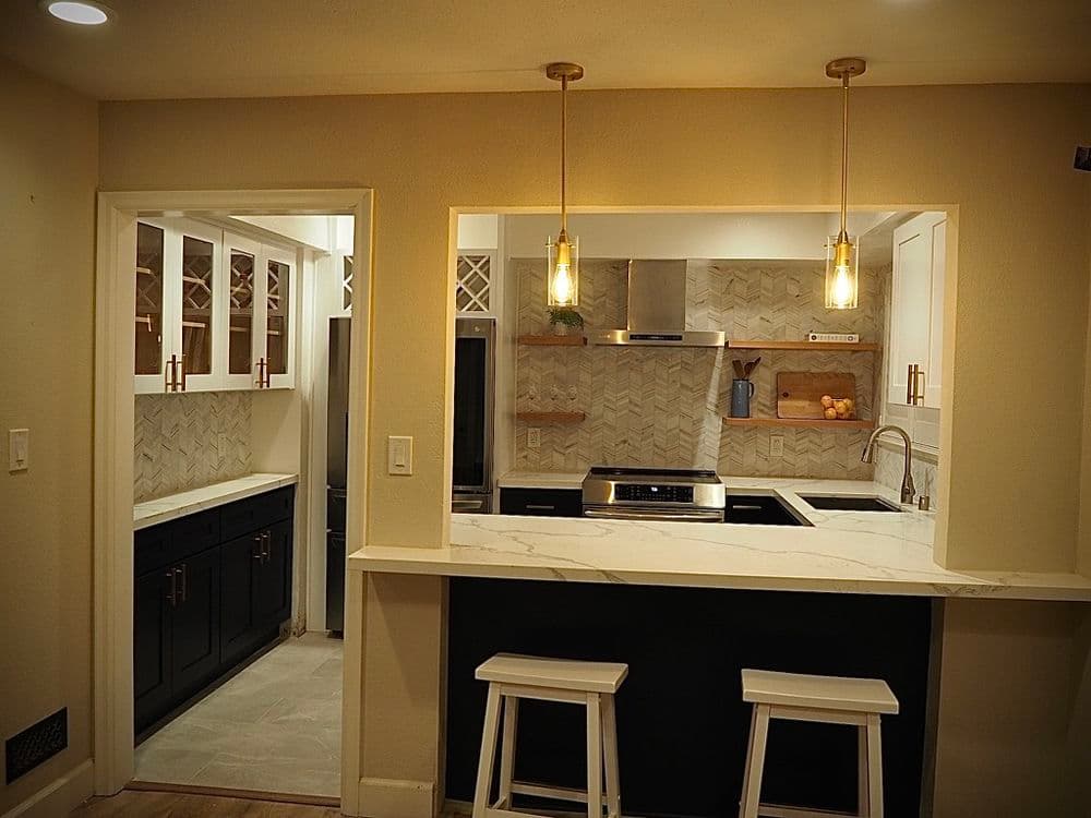 Modern kitchen with black cabinets, marble countertop, and stylish pendant lights.