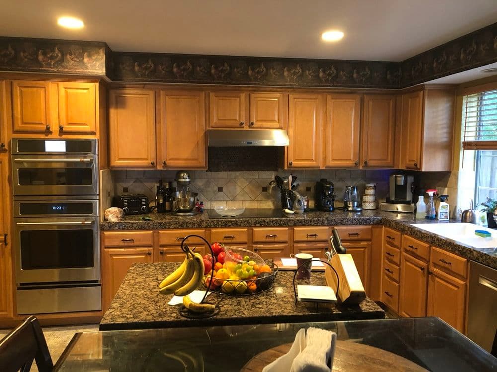 Spacious kitchen with wooden cabinets, granite countertops, and a bowl of fresh fruit.