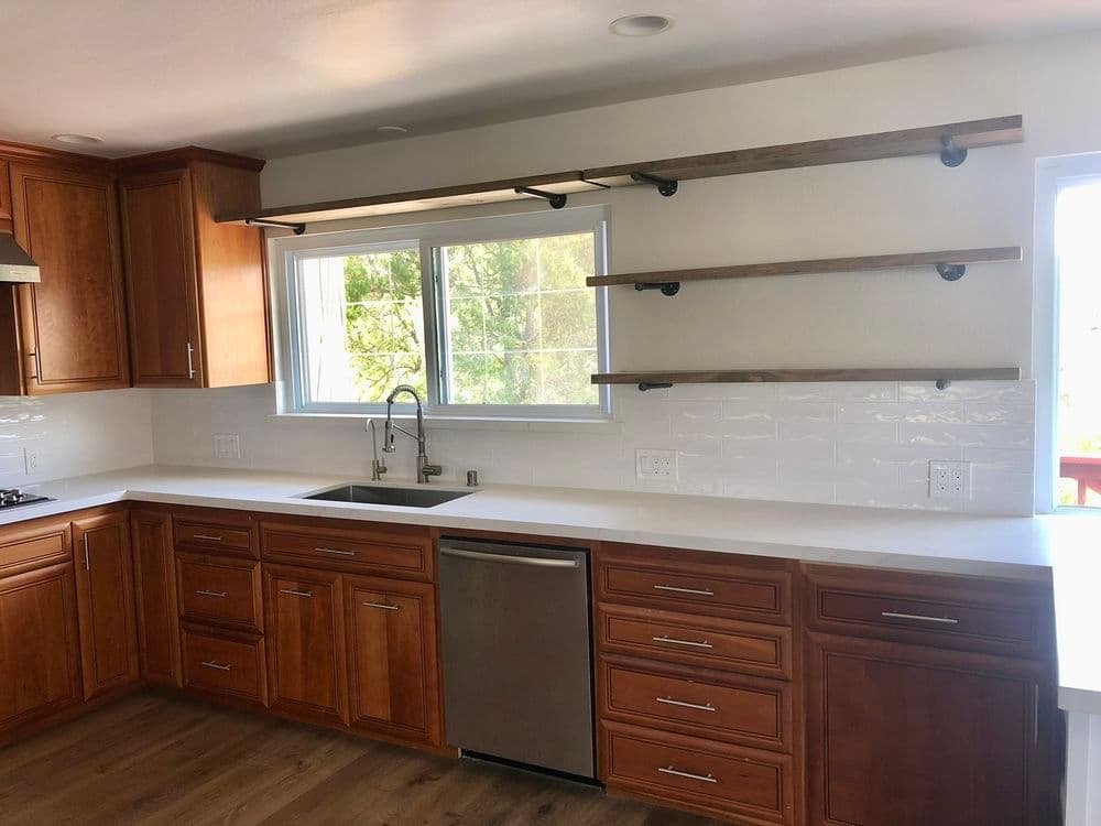 Modern kitchen with wooden cabinets, open shelves, stainless steel sink, and white countertops.