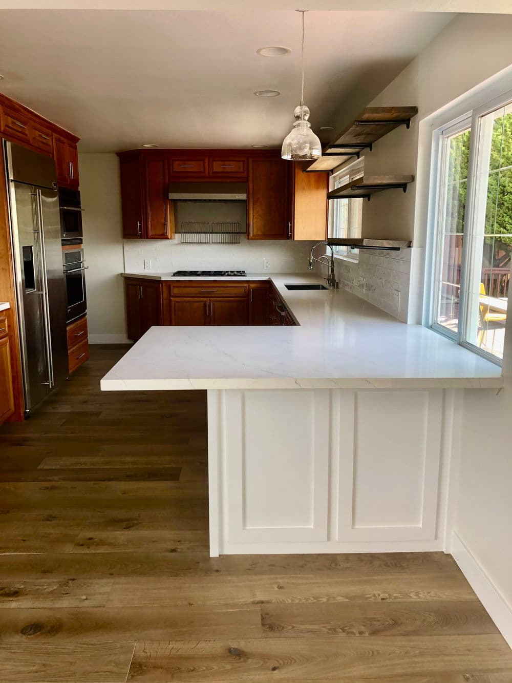 Modern kitchen with wooden cabinets, marble countertop, and open shelving. Bright natural light.