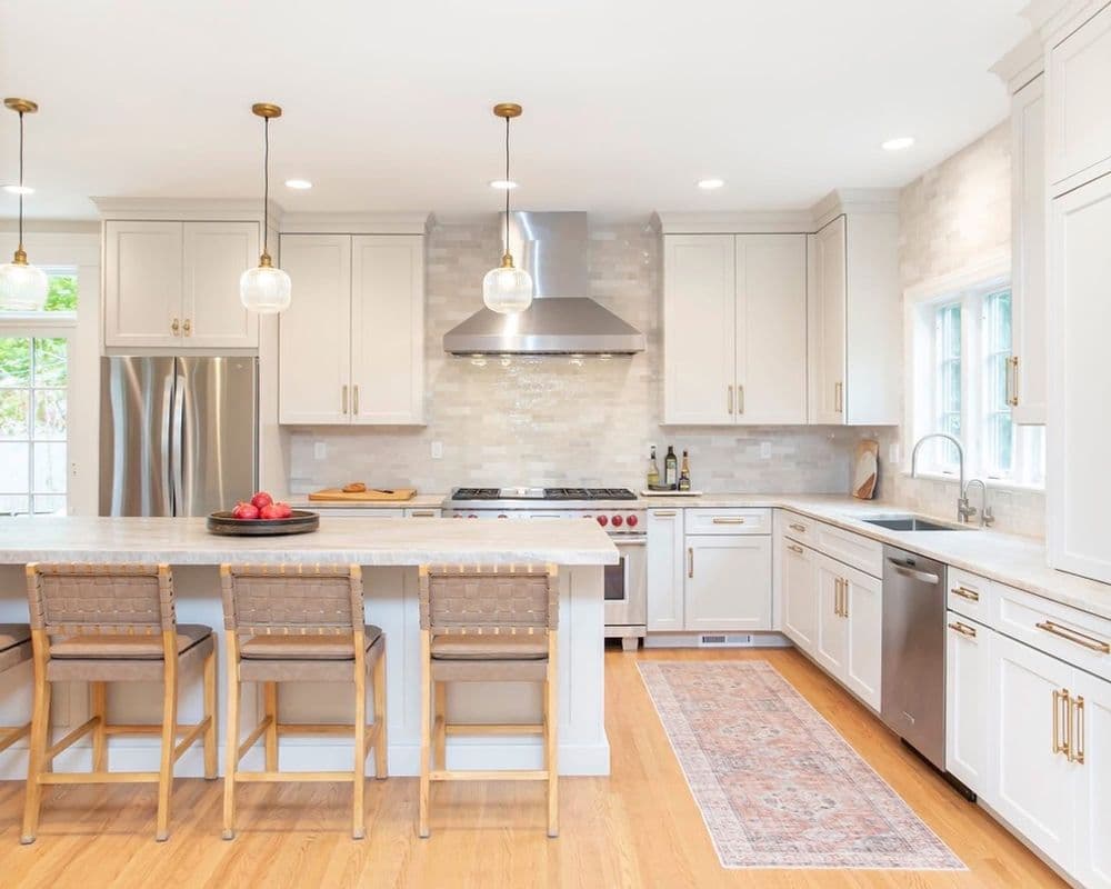 Modern kitchen with white cabinetry, stainless steel appliances, and a spacious island with seating.