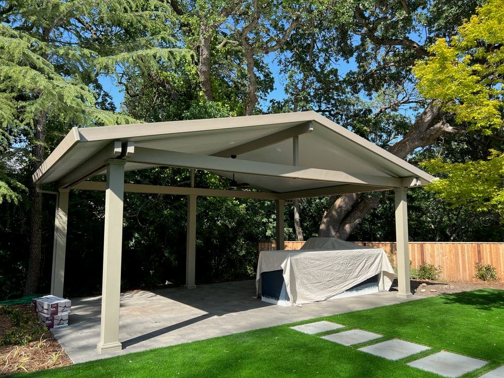 Modern outdoor gazebo with covered patio and landscaping under a clear blue sky.