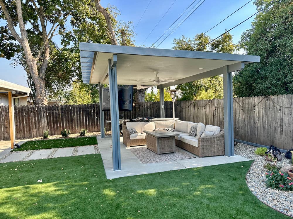 Modern outdoor patio with a cozy seating area, greenery, and a shaded roof. Perfect for relaxation.