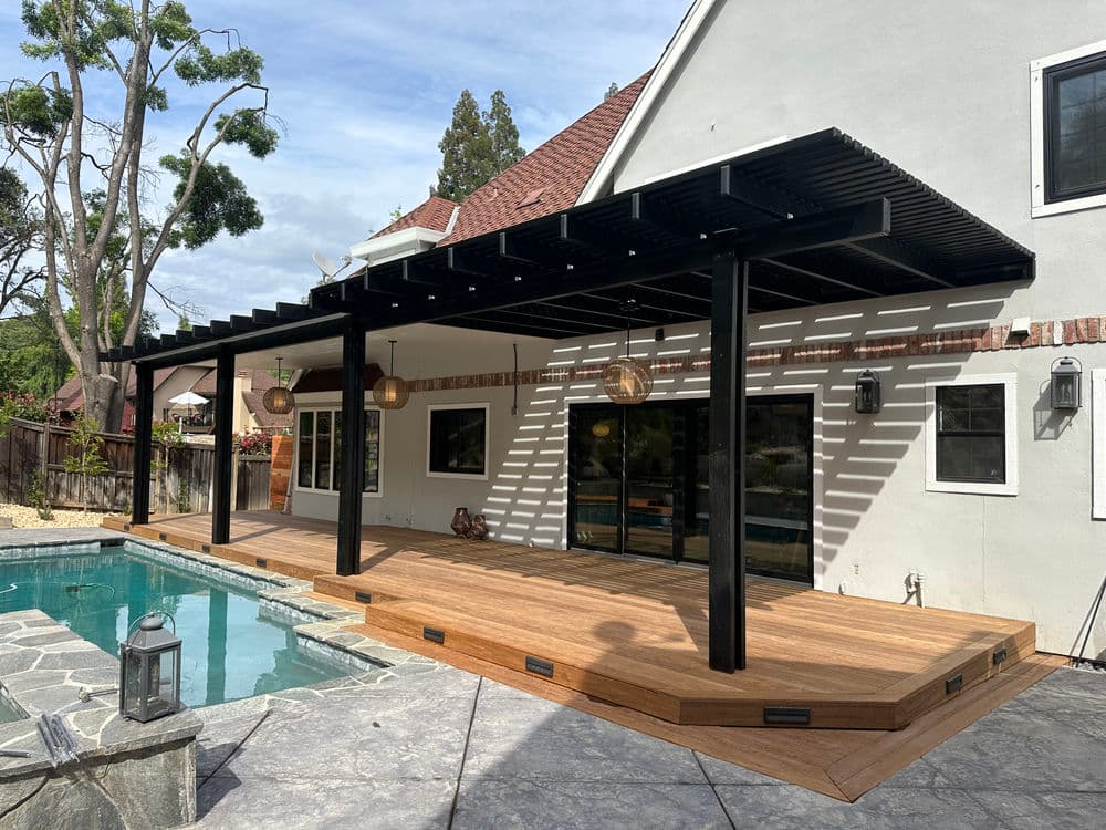 Modern outdoor deck with pergola, pool, and stylish lighting in a landscaped backyard.