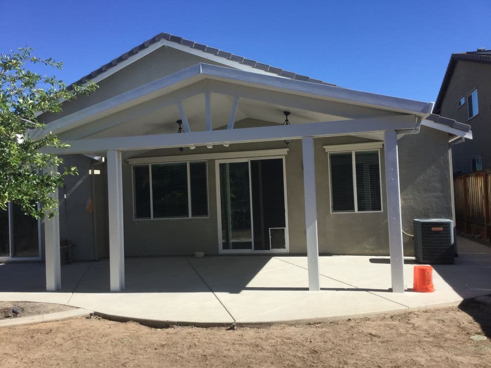 Modern single-story home exterior with covered patio and large windows under a clear blue sky.
