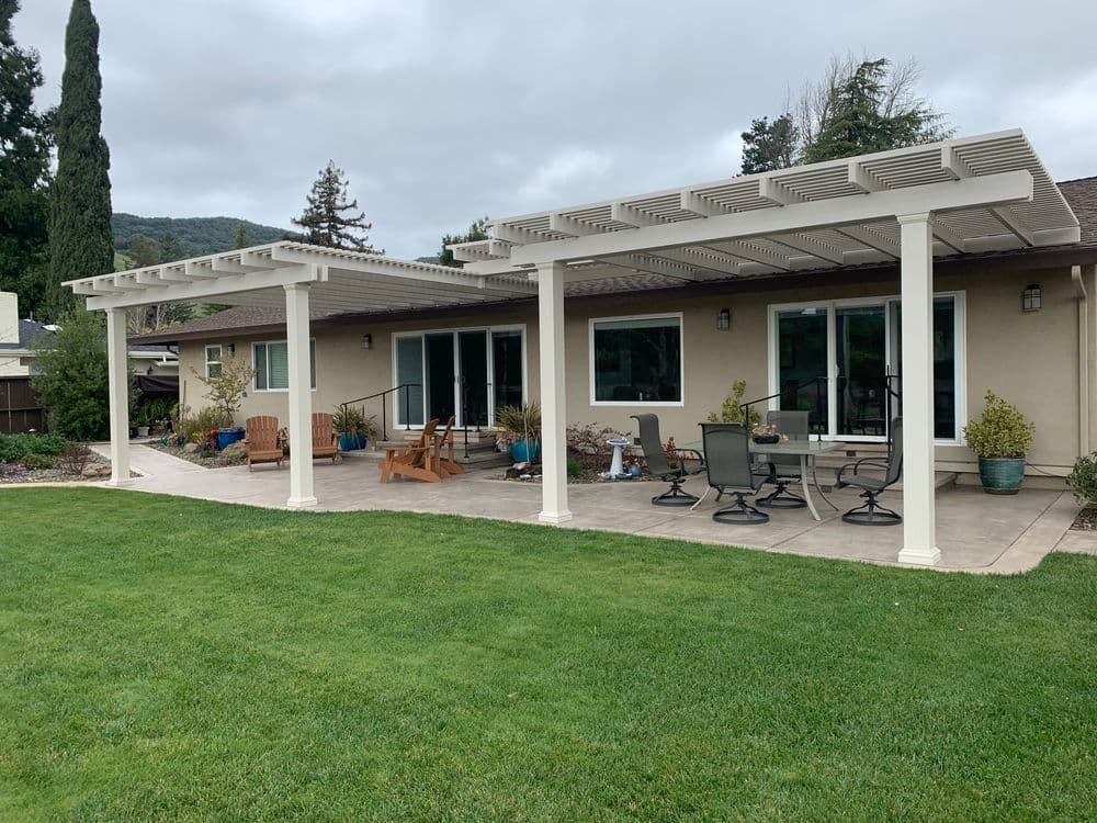 Patio with white pergola, outdoor furniture, and lush green lawn in a residential setting.