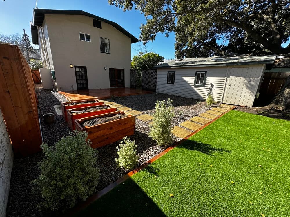 Modern backyard with raised vegetable beds, stone pathway, and green artificial grass.