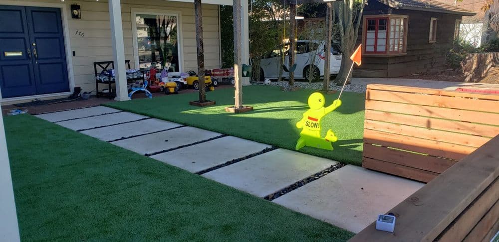 Front yard with artificial grass, a "Slow" sign, and toy vehicles visible in the background.