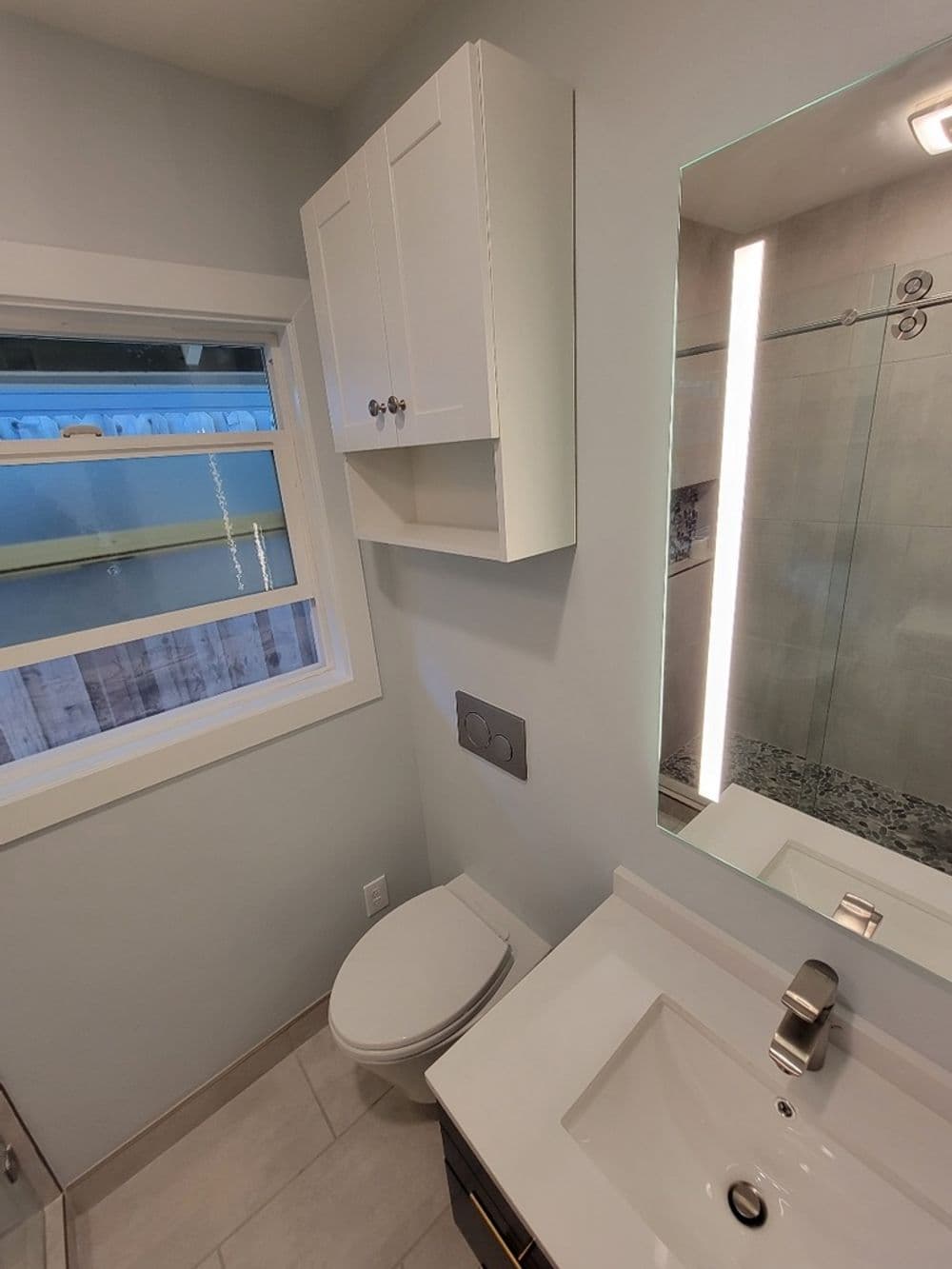 Modern bathroom design featuring a sleek vanity, large mirror, and stylish cabinetry.