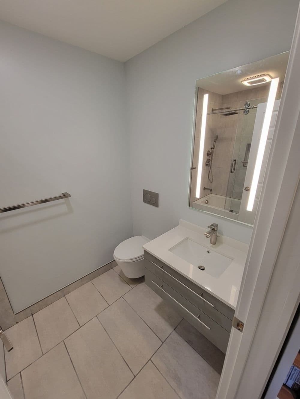 Modern bathroom design featuring a sleek vanity, mirror, shower, and minimal decor.