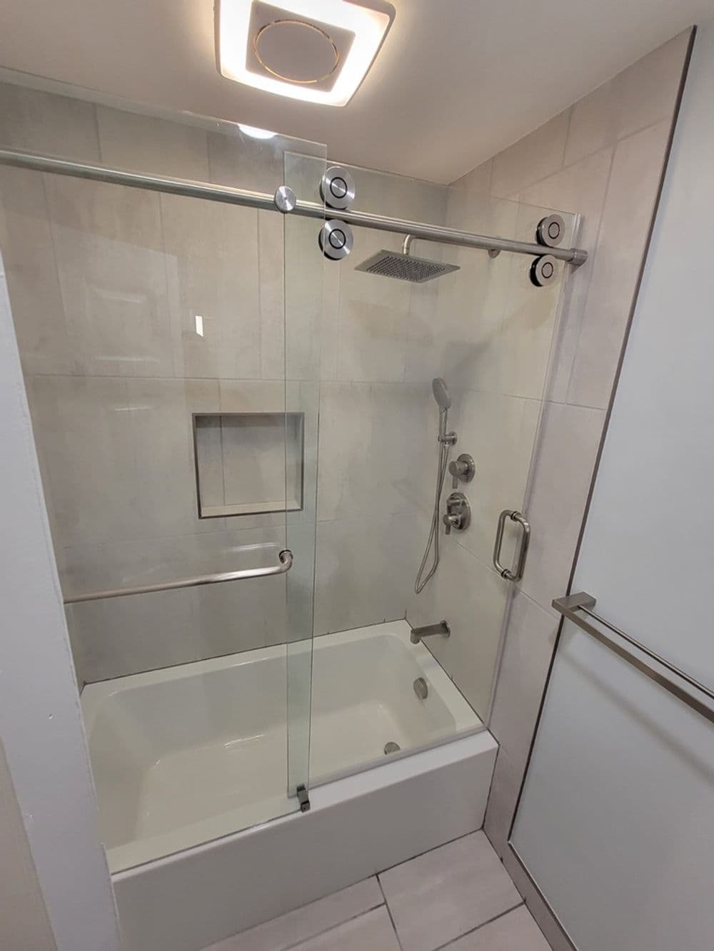 Modern bathroom with a glass shower enclosure and a bathtub, featuring sleek fixtures.