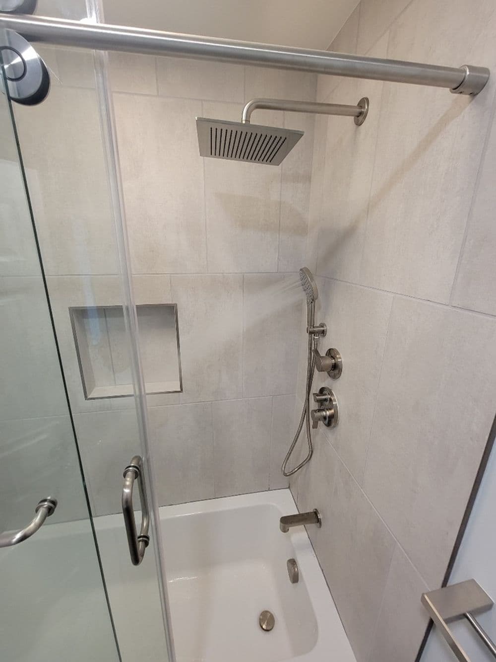 Modern shower with glass enclosure, overhead rain showerhead, and sleek fixtures.