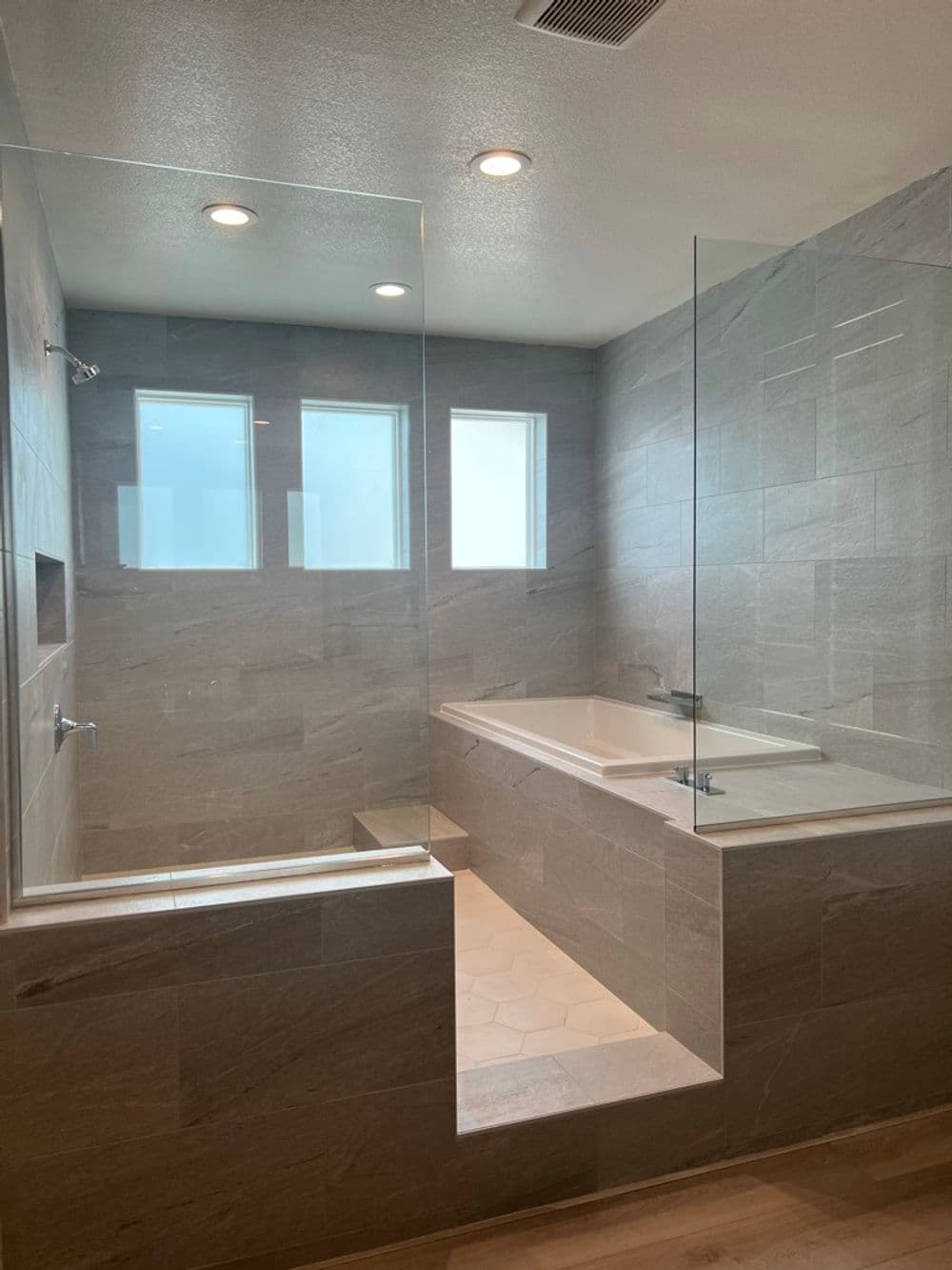 Modern bathroom featuring a glass shower, freestanding bathtub, and natural light from windows.