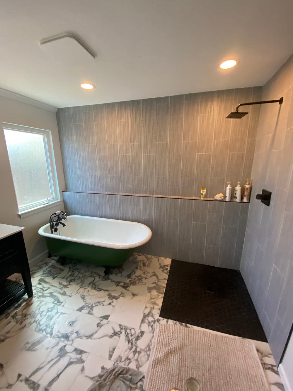 Modern bathroom with a vintage clawfoot tub, marble floor, and sleek shower design.