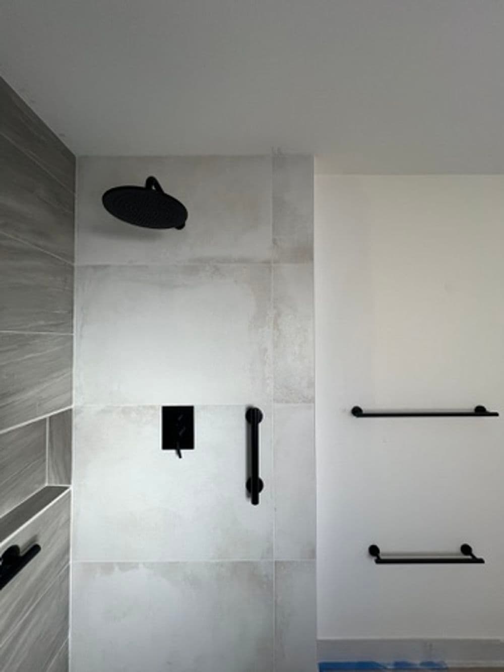 Modern shower setup featuring a black rain showerhead and sleek wall-mounted bars.