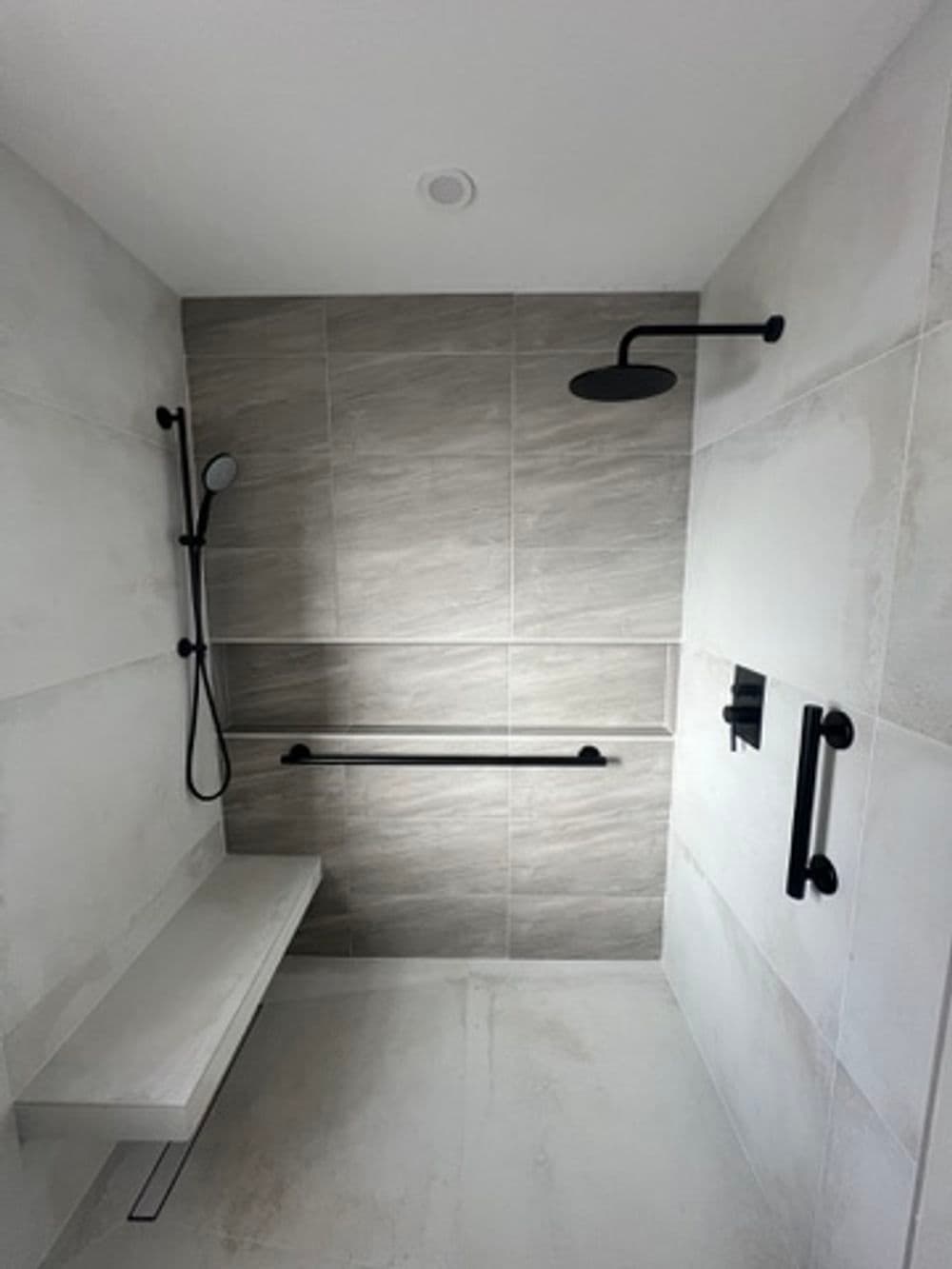 Modern shower design featuring gray tiles, black fixtures, and a sleek bench.