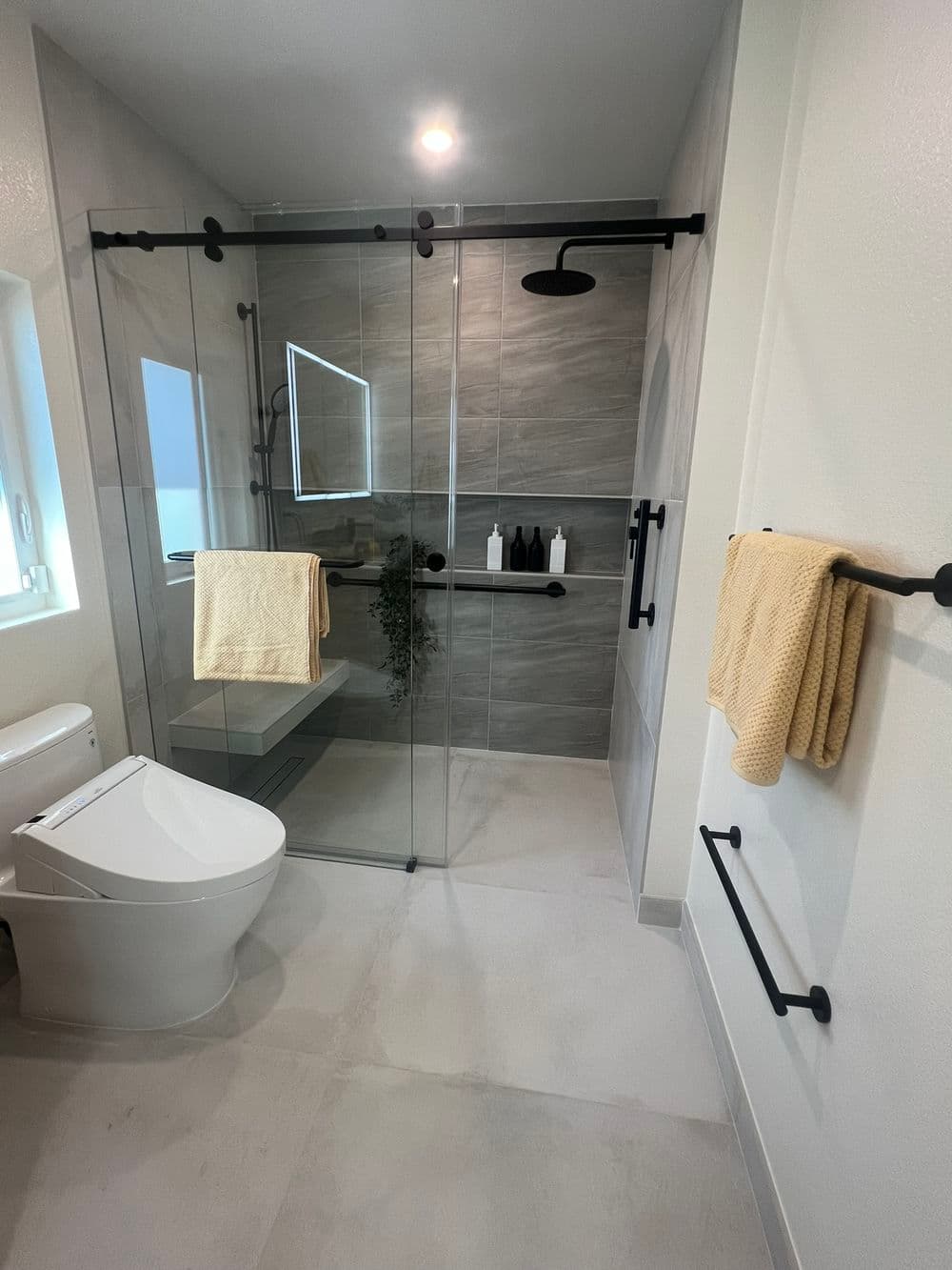 Modern bathroom featuring glass shower, sleek fixtures, and neutral tile design.
